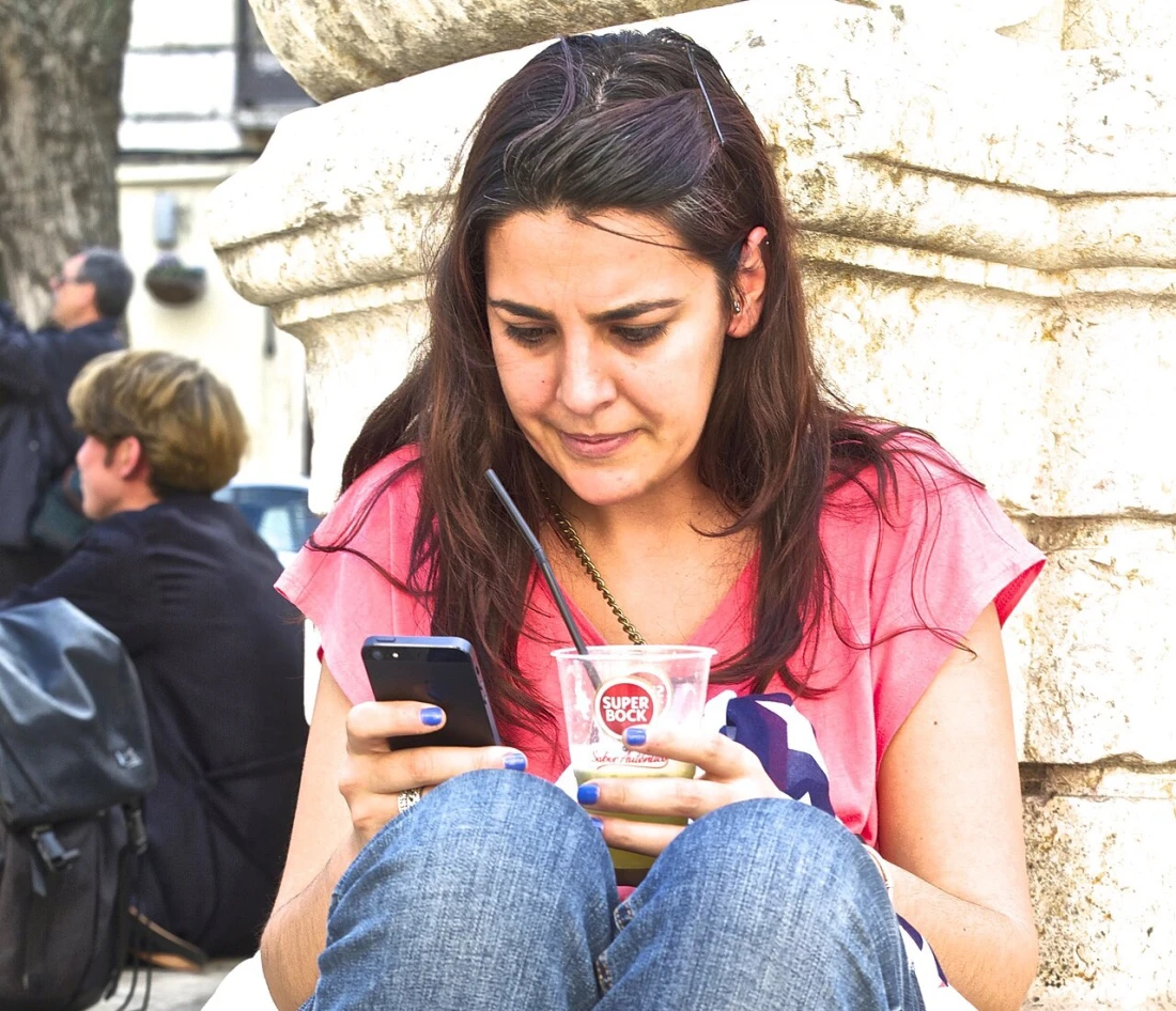A woman sits on a stone step reading something on her phone